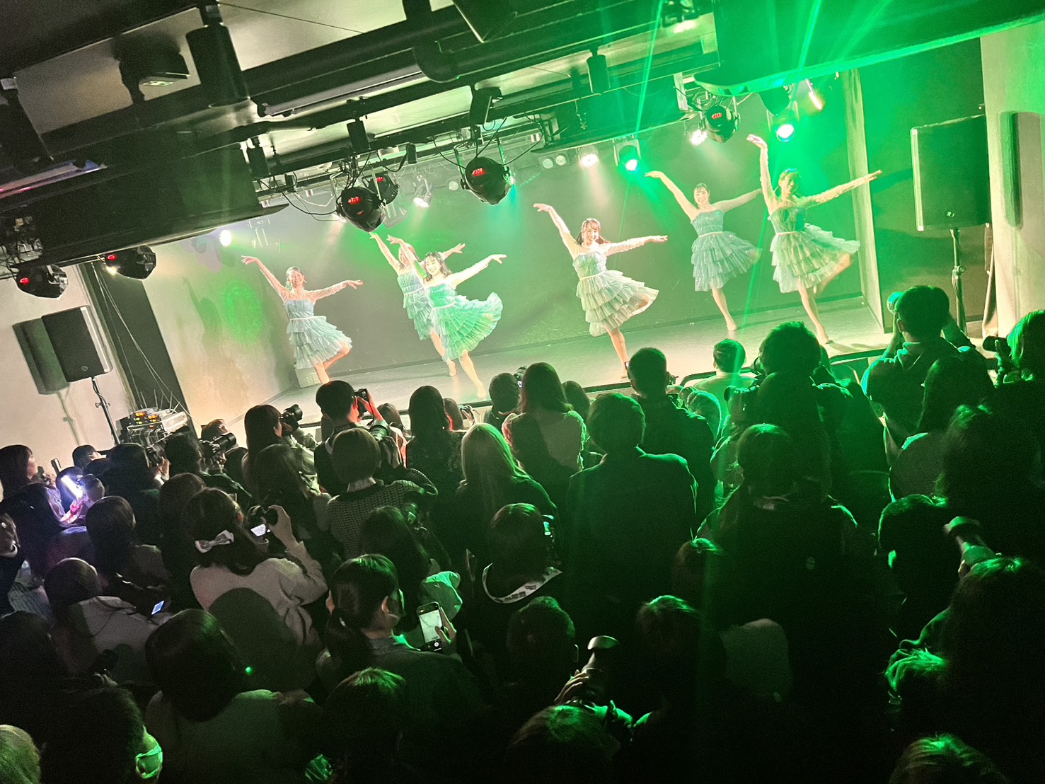 緑の照明の中で踊る出演者と観客