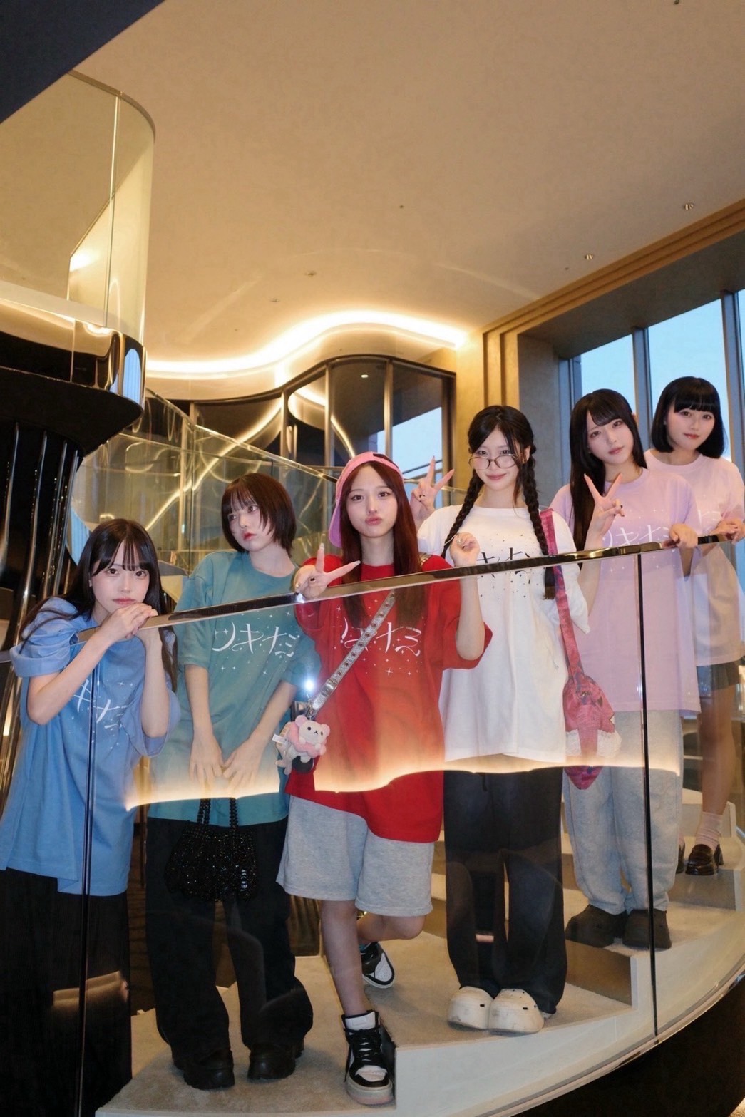 色とりどりのTシャツで階段に集まるツキナミのメンバー